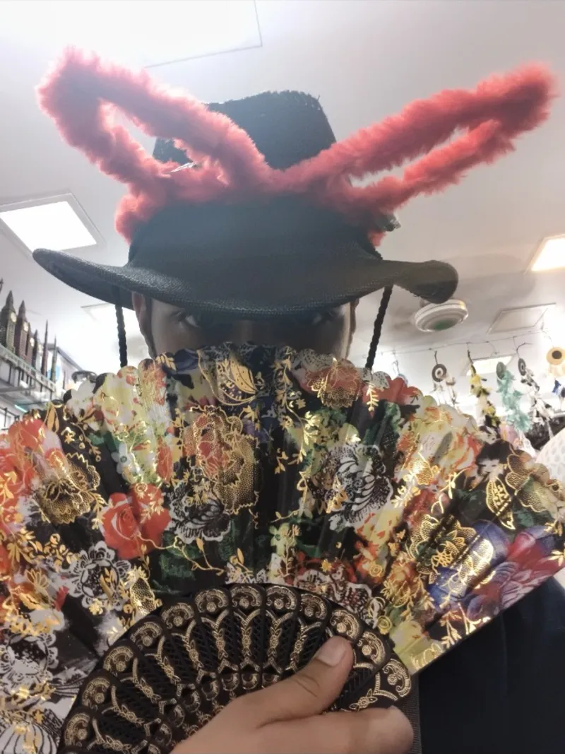 Hardik behind a paper fan wearing fluffy bunny ears on a hat